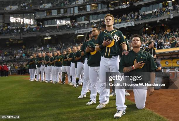 Bruce Maxwell of the Oakland Athletics kneels in protest next to teammate Mark Canha duing the singing of the National Anthem prior to the start of...