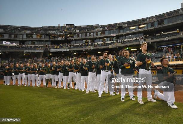 Bruce Maxwell of the Oakland Athletics kneels in protest next to teammate Mark Canha duing the singing of the National Anthem prior to the start of...
