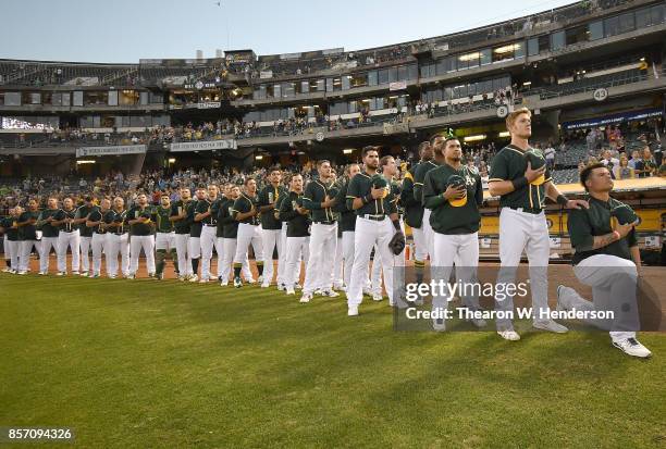 Bruce Maxwell of the Oakland Athletics kneels in protest next to teammate Mark Canha duing the singing of the National Anthem prior to the start of...