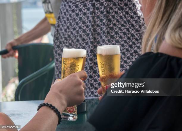 Tourists drink Super Bock draught beer at a terrace bar in the viewpoint of Santa Catarina, a spot favored by visitors, on October 01, 2017 in...