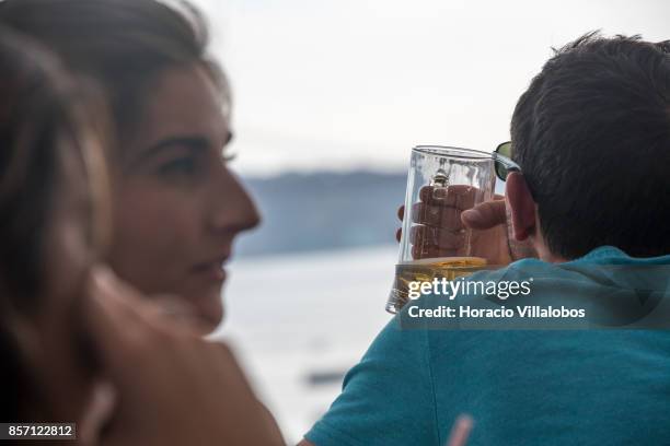 Tourists drink Super Bock draught beer at a terrace bar in the viewpoint of Santa Catarina, a spot favored by visitors, on October 01, 2017 in...