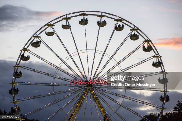 Ferris wheel is seen at dusk at an amusement area set up along 17th of June Street in Tiergraten Park near the Brandenburg Gate on German Unity Day...