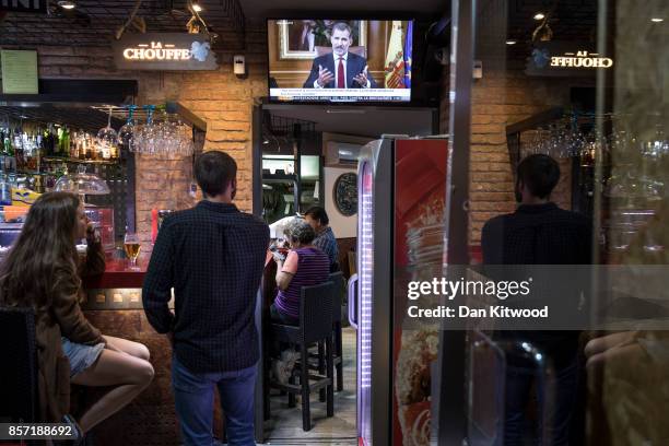 People watch through a bar window as King Felipe VI of Spain, addresses the nation regarding the Catalonian referendum vote, which took place last...