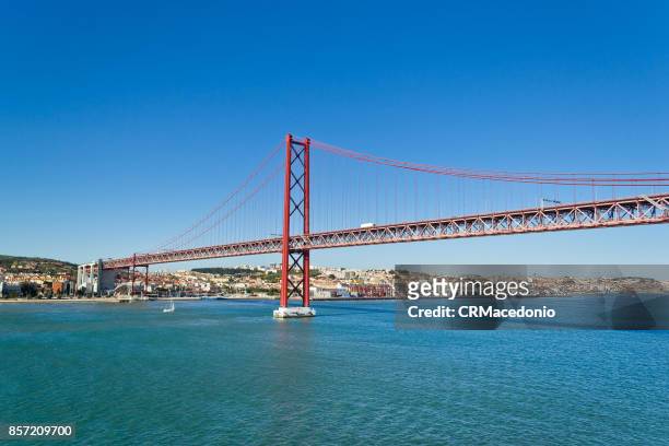 the 25 de abril bridge (ponte 25 de abril) under blue sky. - crmacedonio stock-fotos und bilder