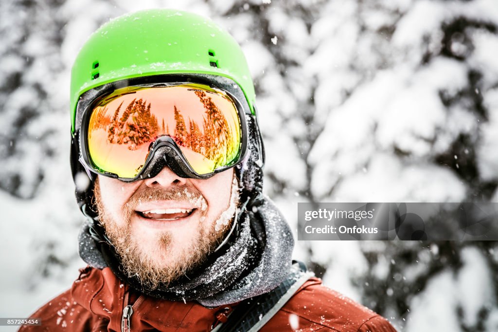 Snowboarder feliz vistiendo casco y gafas en la montaña del esquí