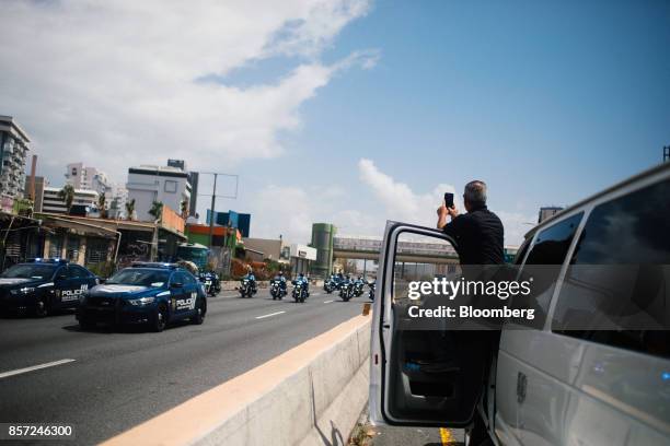 Person steps out of a vehicle to take a photograph with a smartphone of U.S. President Donald Trump's motorcade in San Juan, Puerto Rico, on Tuesday,...