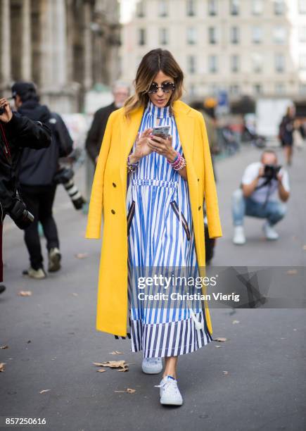 Guest wearing blue white striped dress, yellow coat seen outside Thom Browne during Paris Fashion Week Spring/Summer 2018 on October 3, 2017 in...