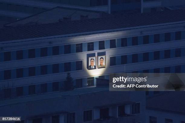 This photo taken on November 25, 2016 shows the illuminated portraits of late North Korean leaders Kim Il-Sung and Kim Jong-Il amid the night skyline...