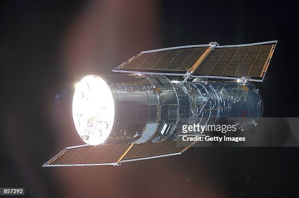 The Hubble Space Telescope is backdropped against black space as the Space Shuttle Columbia, with a crew of seven astronauts on board, eases closer...