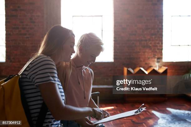 two young women looking at welcome note, after arriving to rental apartment - woman blond looking left window photos et images de collection