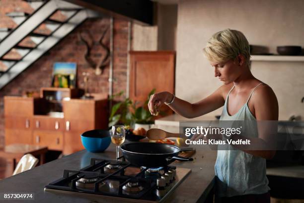 young woman cooking in loft apartment - burner stove top stockfoto's en -beelden