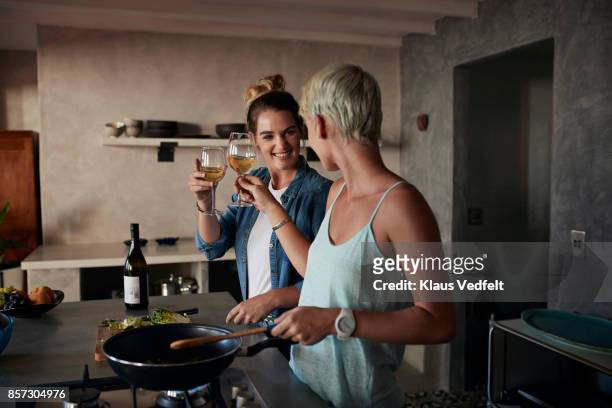 two young women cooking together in loft apartment, toasting in wine - alcohol and women stock-fotos und bilder