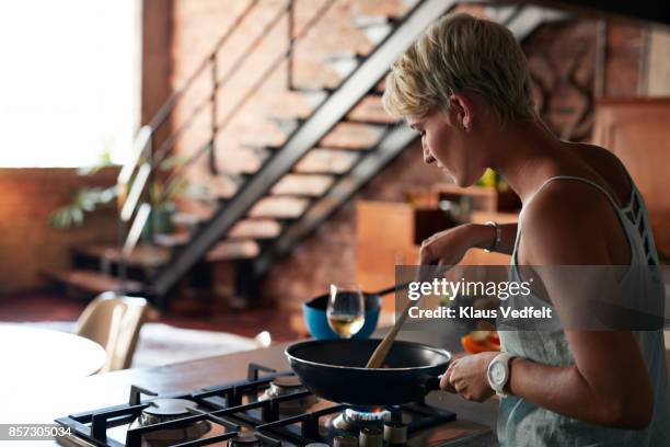 young woman cooking in loft apartment - boca de fogão a gás - fotografias e filmes do acervo