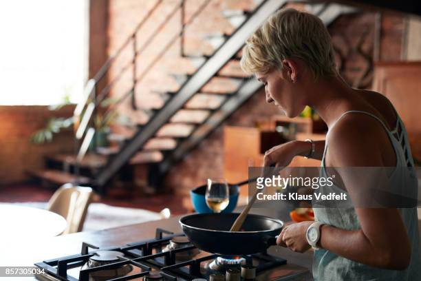 young woman cooking in loft apartment - gasspis bildbanksfoton och bilder