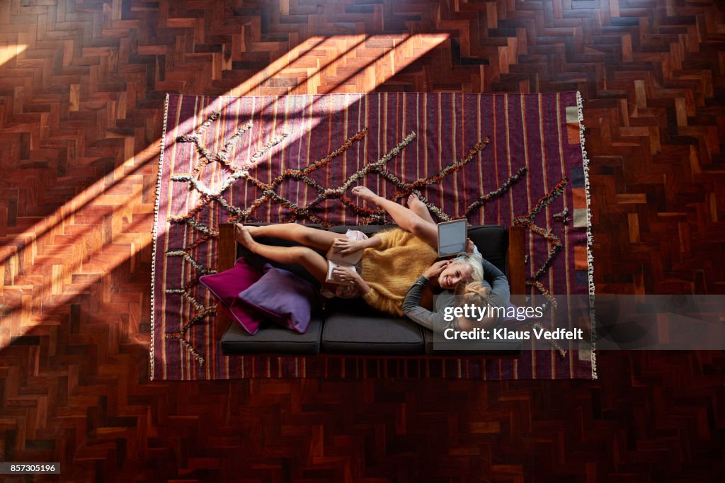 Lesbian couple relaxing and reading in couch