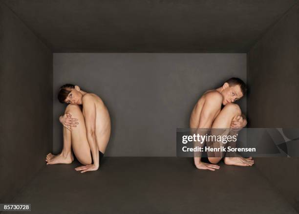 young pair trapped inside a small black room - abbracciare le ginocchia foto e immagini stock