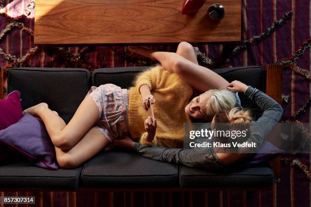 lesbian couple relaxing and reading in couch - young people looking at camera foto e immagini stock