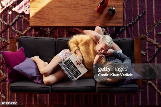Lesbian couple relaxing in sofa, with laptop
