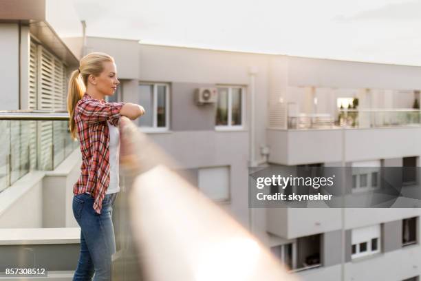 beautiful woman standing on a penthouse terrace and enjoying the view. - women of penthouse stock pictures, royalty-free photos & images