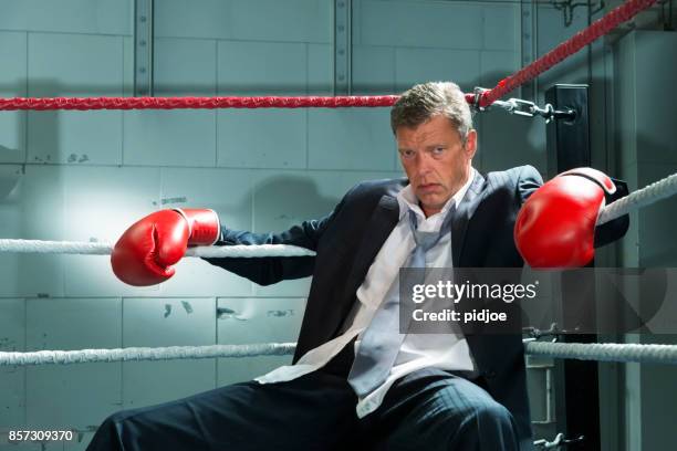 business man knocked out in corner of box ring - boxing ring stock pictures, royalty-free photos & images