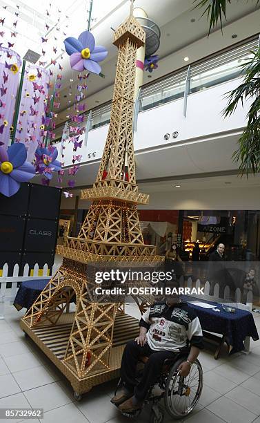 Wheelchair-bound Lebanese craftsman Tufiq Daher poses next to his matchstick model of the Eiffel Tower at a shopping mall outside Beiurt on March 31,...