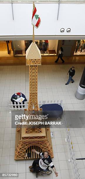 Wheelchair-bound Lebanese craftsman Tufiq Daher poses next to his matchstick model of the Eiffel Tower at a shopping mall outside Beiurt on March 31,...