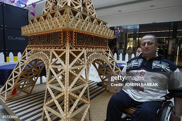 Wheelchair-bound Lebanese craftsman Tufiq Daher poses next to his matchstick model of the Eiffel Tower at a shopping mall outside Beiurt on March 31,...