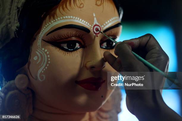 Woman of a traditional artistic family applying colors into the idol of wealth goddess Lakshmi ahead of the Lakshmi Puja festival at a village...