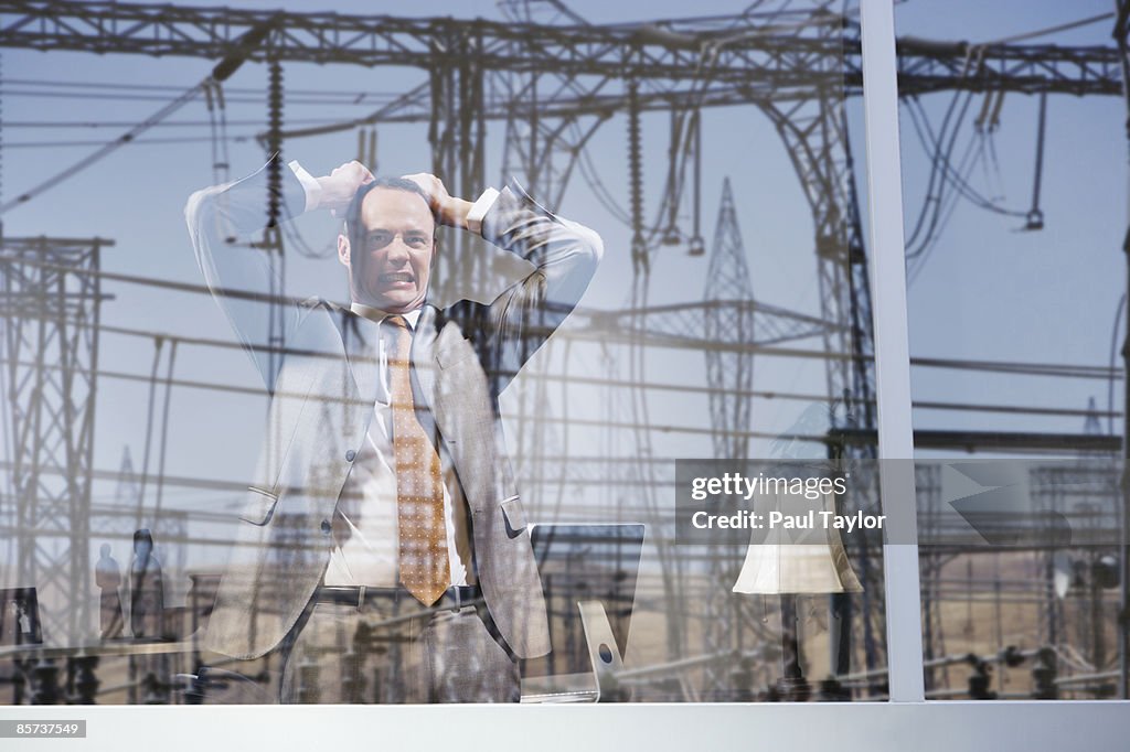 Businessman in office with reflection of powerline