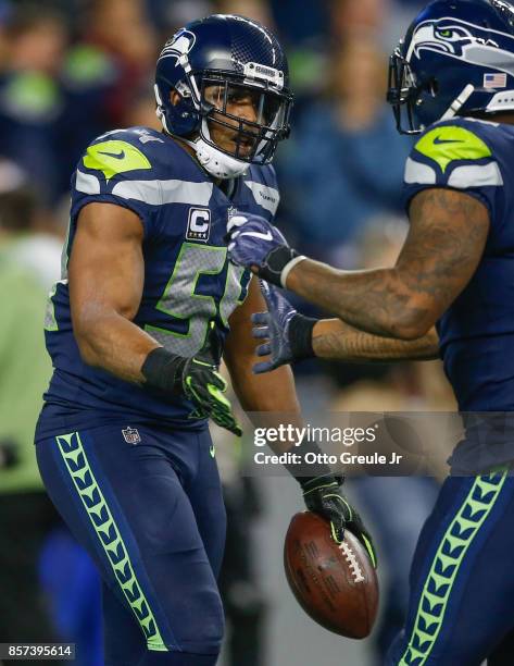 Middle linebacker Bobby Wagner of the Seattle Seahawks is congratulated by defensive end Marcus Smith after returning a fumble recovery for a...