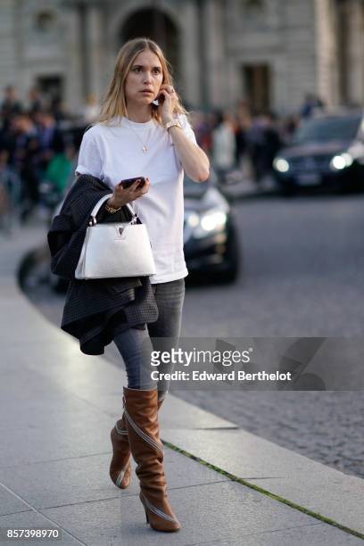 Pernille Teisbaekwears a white t)shirt, a white bag, boots, gray pants, outside Louis Vuitton, during Paris Fashion Week Womenswear Spring/Summer...