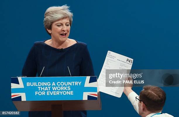 Protester comedian Simon Brodkin gives a piece of paper written as a mock P45 to Britain's Prime Minister Theresa May as she was delivering her...