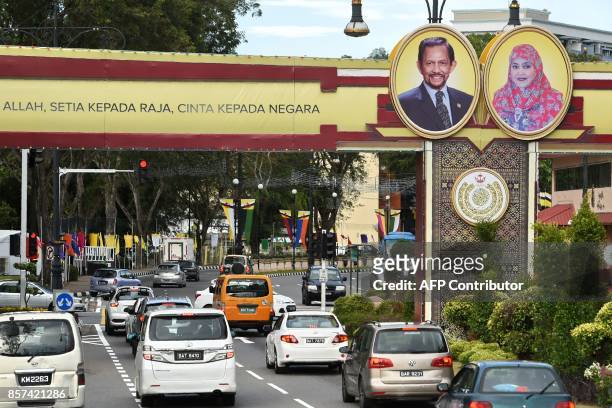 Portraits of Brunei's Sultan Hassanal Bolkiah and Queen Saleha are seen beside a slogan in Bahasa Melayu that reads "obedience to Allah, loyalty to...