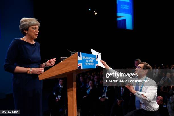 Protester comedian Simon Brodkin delivers a piece of paper written as a mock P45 to Britain's Prime Minister Theresa May as delivers her speech on...