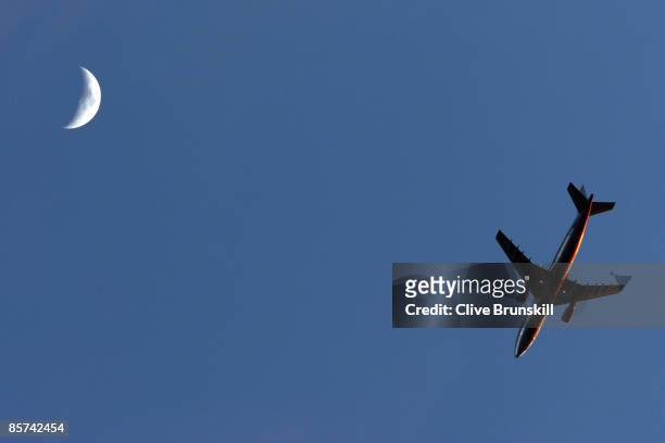 Plane flies past the moon as Roger Federer of Switzerland takes on Taylor Dent during day nine of the Sony Ericsson Open at the Crandon Park Tennis...