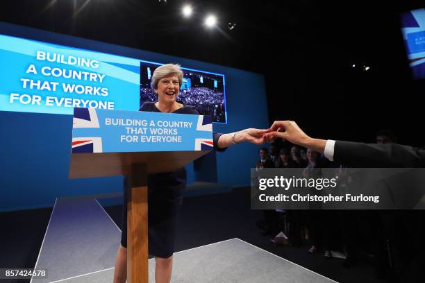 British Prime Minister Theresa May is handed a cough sweet during her keynote speech to delegates and party members on the last day of the...