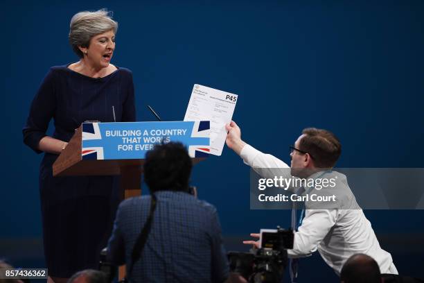 Comedian Simon Brodkin, aka prankster Lee Nelson, hands Prime Minister Theresa May a P45 during her keynote speech to delegates and party members on...