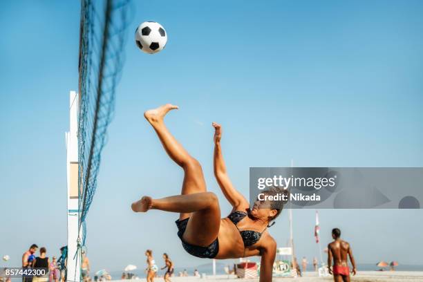 mujer brasileña saltar y patear la pelota en la playa en brasil - volleyball sport fotografías e imágenes de stock