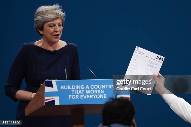 Comedian Simon Brodkin, aka prankster Lee Nelson, hands Prime Minister Theresa May a P45 during her keynote speech to delegates and party members on...