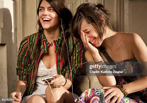 two girlfriends sharing mp3-player - sharing headphones stock pictures, royalty-free photos & images