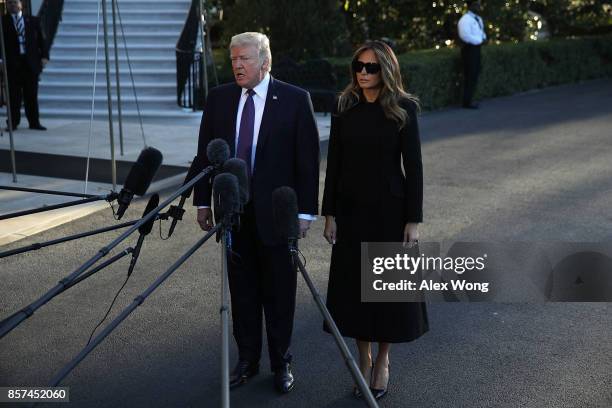 President Donald Trump speaks to members of the media as first lady Melania Trump looks on prior to his departure from the South Lawn of the White...