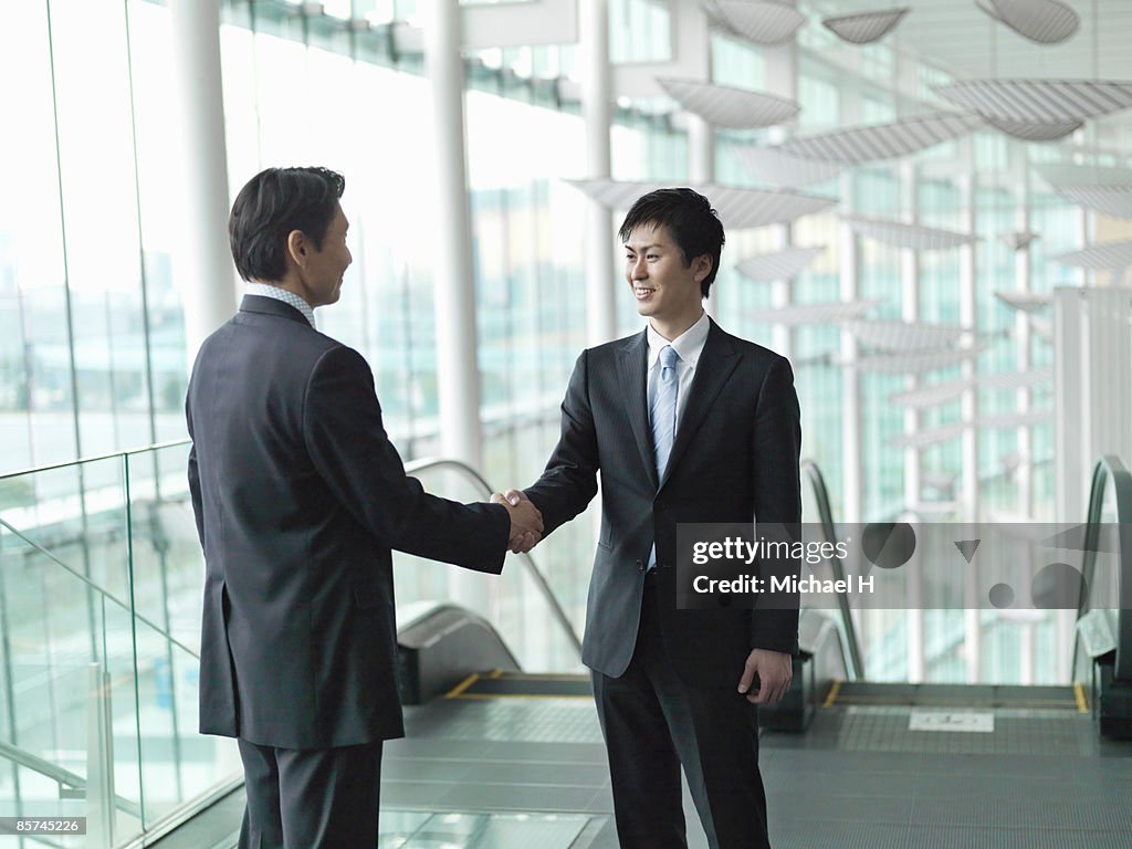 Businessman who shakes hands in escalator hall