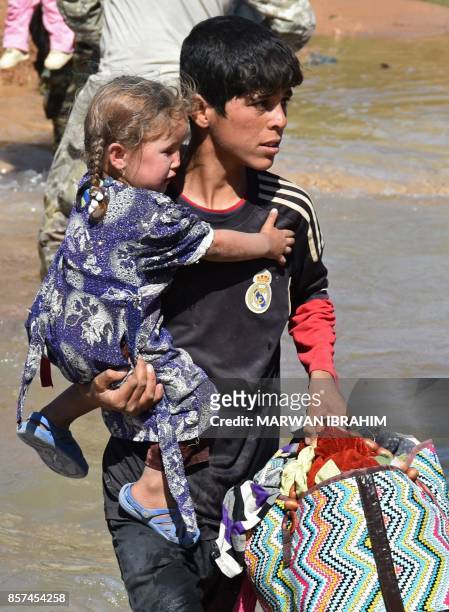 Displaced Iraqis who fled from the ongoing battles to oust the Islamic State group from Hawija, cross a river in the area of Zarga some 35 kilometres...