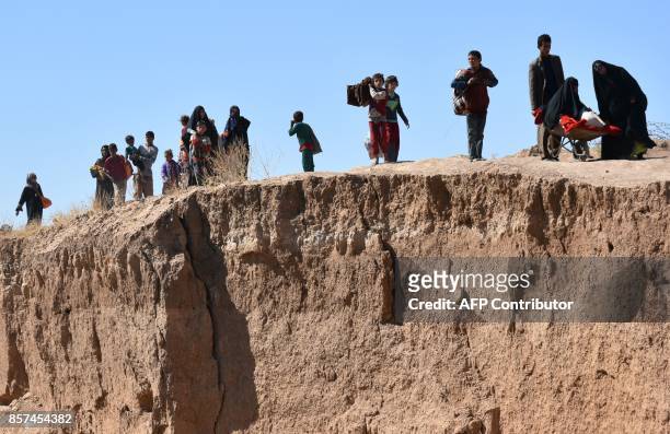 Displaced Iraqis who fled from the ongoing battles to oust the Islamic State group from Hawija, walk a long the bank of a river in the area of Zarga...