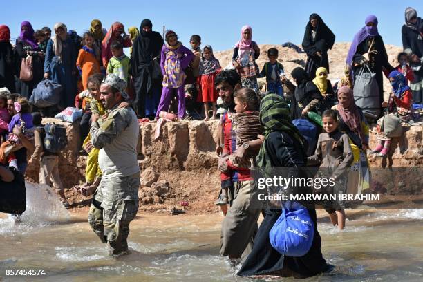 Fighters from the Hashed al-Sahaabi units and Kurdish Pershmerga batallions help displaced Iraqis, who fled from the ongoing battles to oust the...