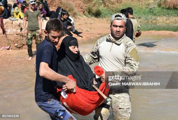 Fighter from the Hashed al-Sahaabi units helps to carry an elderly displaced woman who fled from the ongoing battles to oust the Islamic State group...