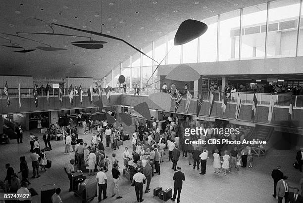 High-angle interior view of the International Arrival Building at John F. Kennedy International Airport shows a crowd of passengers as they stand...
