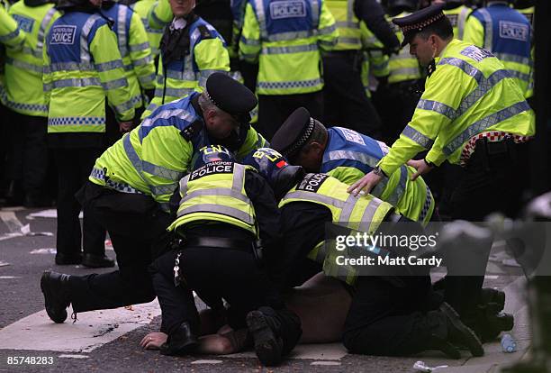 Climate change and anti-capitalist activist is detained by police during a demonstration outside a branch of the Royal Bank of Scotland on April 1,...