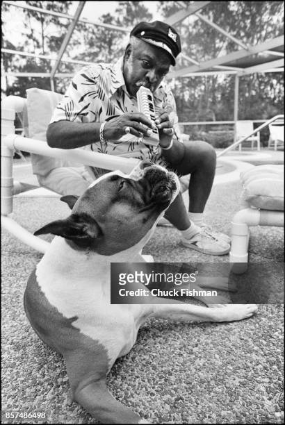 American Jazz and Swing musician Count Basie plays a melodica, accompanied by his bulldog Graf, as they sit poolside at his home, Freeport, Bahamas,...