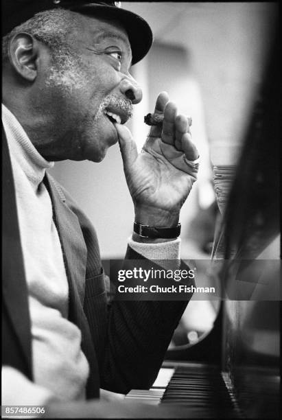 Close-up of American Jazz and Swing musician Count Basie as he smokes a cigar at a piano during a studio rehearsal, New York, New York, January 1982.